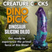 Blue, purple, teal, and black dinosaur-themed silicone dildo with textured details and suction cup base on forest background.
