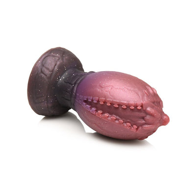 Large glittery red and brown silicone dragon egg plug with textured ridges and a tapered tip on a white background.
