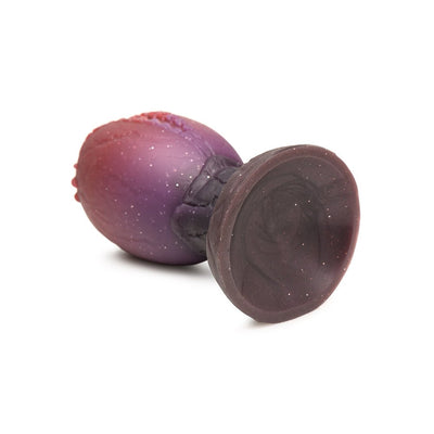 Large silicone dragon egg plug with glittery red and purple hues, textured ridges, and wide base for safe use.