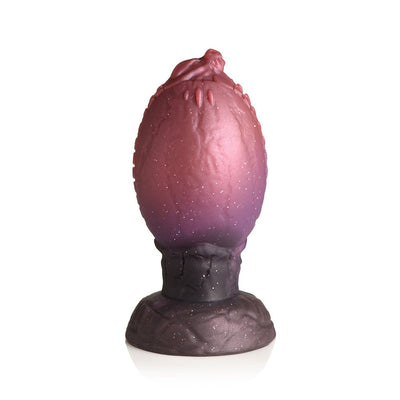 Large dragon egg-shaped silicone plug with glittery red to purple gradient and textured dragon head tip.