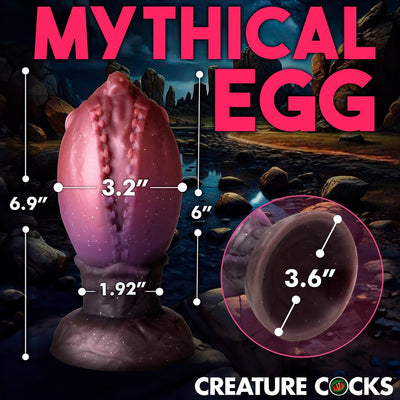 Red and brown dragon egg plug with textured ridges and wide base, shown with size measurements against a fantasy landscape background.