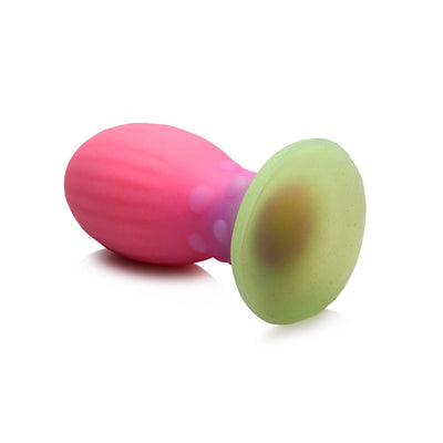 Large multi-color glow-in-the-dark silicone egg with ribbed pink body and green base for textured stimulation.