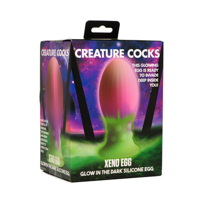 Packaging box of Creature Cocks Xeno Egg, a large glow-in-the-dark silicone egg with pink and green colors.