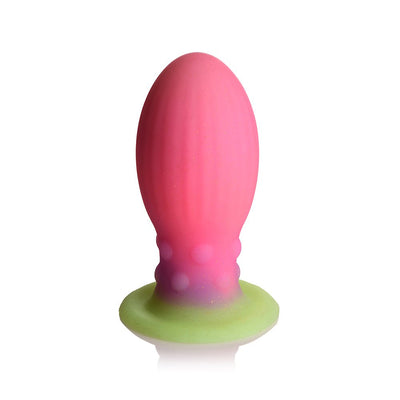 Large silicone egg-shaped plug in pink, purple, and green with ribbed texture and raised bumps, designed to glow in the dark.