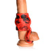 Red and black silicone girth enhancer with ball strap on a realistic flesh-toned model.