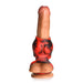 Red and black silicone girth enhancer and ball strap sleeve on a realistic flesh-toned dildo with suction base.