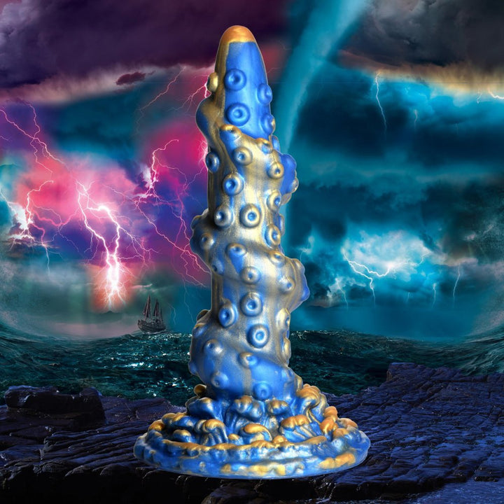 Blue and gold silicone dildo with tentacle-like texture and suction cup base against a stormy ocean background.