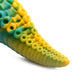 Close-up of green and yellow silicone tentacle dildo with detailed suction cups on textured surface.