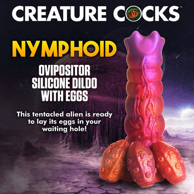 Sunset-colored silicone ovipositor dildo with textured ribs, alien symbol, and detachable egg-shaped inserts on a sci-fi background.