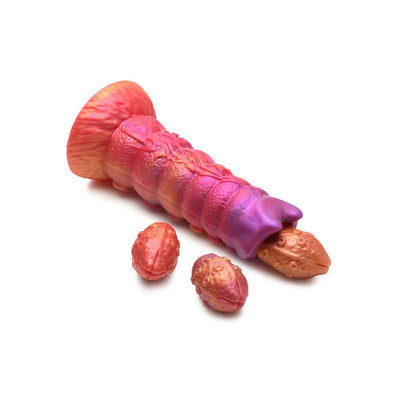 Sunset-colored silicone ovipositor dildo with textured shaft and two removable egg-shaped inserts on white background.