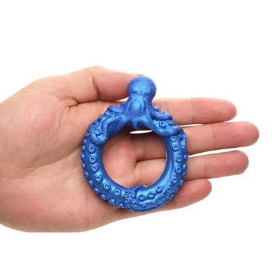 Hand holding a blue silicone octopus-shaped ring with detailed tentacles designed as a stretchy C-ring accessory.