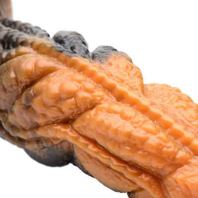 Close-up of textured orange and black rippled silicone dildo with detailed ridges and scales.