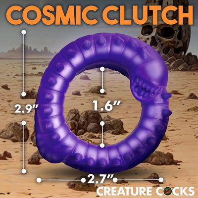 Purple silicone cock ring shaped like a spiked, toothy worm with size measurements on a desert background.