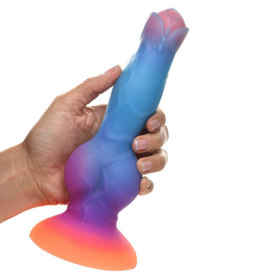 Hand holding a colorful silicone alien-themed dildo with a wide orange base and blue to purple gradient shaft.