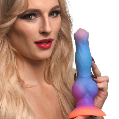 Blonde woman holding a colorful silicone alien dildo with a wide suction base and glowing gradient colors.