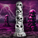 White and gray silicone dildo shaped as a tower of stacked skulls with a suction cup base against a purple stormy background.