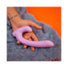Hand holding a lavender curved silicone dual-ended intimate toy on a soft gray textured fabric background.