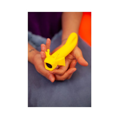Hands holding a bright yellow ergonomic vibrator with playful antennae and fin design for comfortable grip and stimulation.