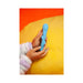 Hands holding a teal silicone toy with playful faces, set against a bright yellow and orange background.