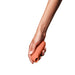 Hand holding a compact, smooth, terracotta-colored Dame Aer Air Pulse Stimulator with a rounded opening.
