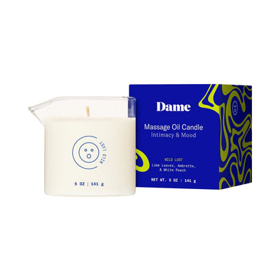 Dame Massage Oil Candle in clear glass with easy-pour spout next to blue and green patterned box packaging.