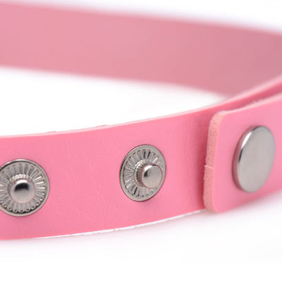 Close-up of pink vegan leather choker strap with silver snap button closures on white background.