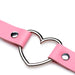 Close-up of pink vegan leather strap with silver metal heart-shaped ring and rivet details on white background.