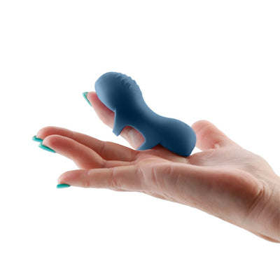 Blue silicone finger massager held on an open hand with teal nail polish, showing its flexible design and size.