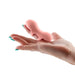 Hand holding a soft pink silicone finger massager with a textured tip and open finger slot design.