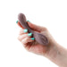 Hand holding a compact mauve silicone Desire Pure vibrator with textured tip and power button.