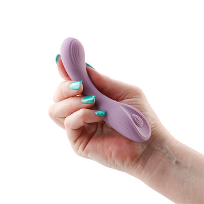 Hand holding a lavender Desire Pure silicone vibrator with textured surface and power button on white background.