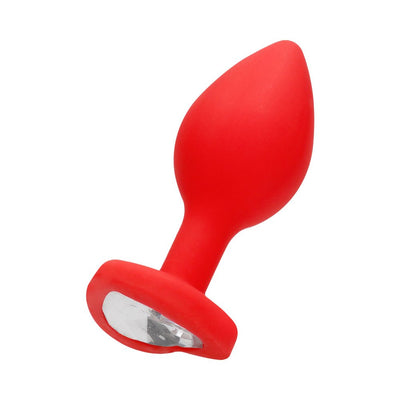 Large red silicone butt plug with tapered shape and clear diamond-shaped gem at the flared base.