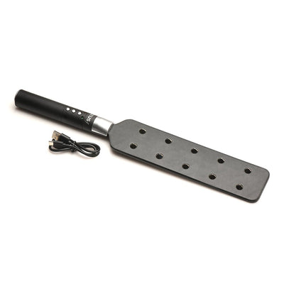 Black e-stim paddle with ten metal spikes on one side, ergonomic handle with control buttons, and USB charging cable.