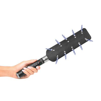 Hand holding a black e-stim paddle with 10 metal spikes emitting electric sparks, featuring control buttons on the handle.