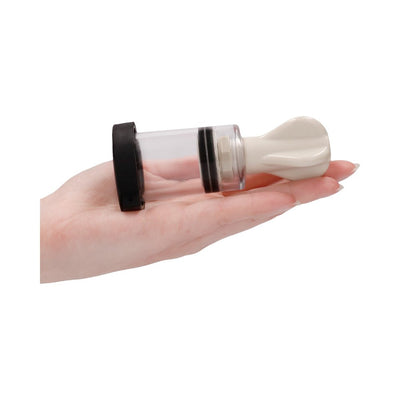 Hand holding a white and transparent electro nipple twister with black accents, designed for adjustable suction and stimulation.