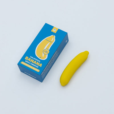 Compact yellow banana-shaped vibrator next to its blue packaging box with playful banana emoji design.