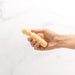 Hand holding a compact, textured pale yellow Emojibator Tiny Wand vibrator against a white background.