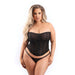 Curvy woman wearing black mesh strapless corset with front zipper and matching G-string panty on white background.