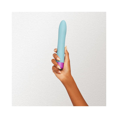 Hand holding a sleek, flexible blue Femme Funn Densa bullet vibrator with a textured purple base against a white background.