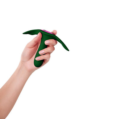 Hand holding a dark green Femme Funn Ossia wearable vibrator with a slim, ergonomic design and pink control buttons.