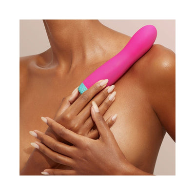Close-up of a person holding a pink and teal FemmeFunn Rora rechargeable silicone rotating bullet vibrator against their shoulder.