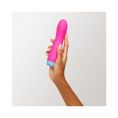 Hand holding a pink FemmeFunn Rora rechargeable silicone rotating bullet vibrator with a blue base against a white background.