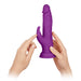 Hands holding a purple wireless Turbo Rabbit vibrator with dual stimulating heads and a suction base.
