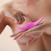 Close-up of a person holding and touching a sleek pink FemmeFunn Unda Panty Vibrator against a neutral background.
