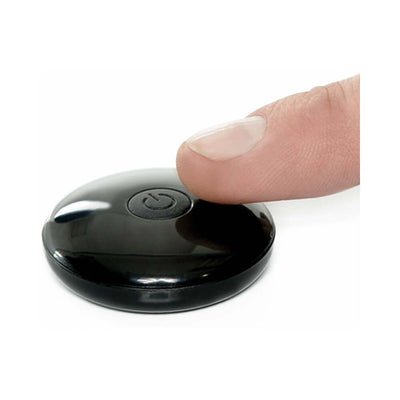 Finger pressing power button on a sleek black remote control for a rechargeable strap-on.