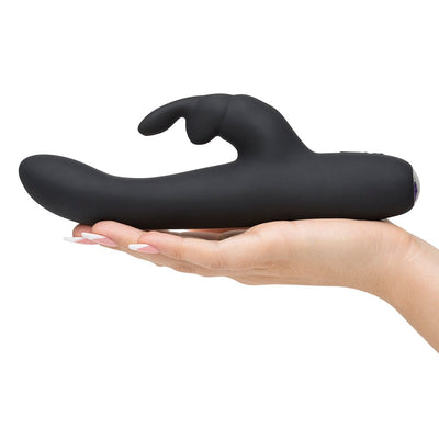 Hand holding a sleek black rechargeable slimline rabbit vibrator with curved shaft and clitoral stimulator.