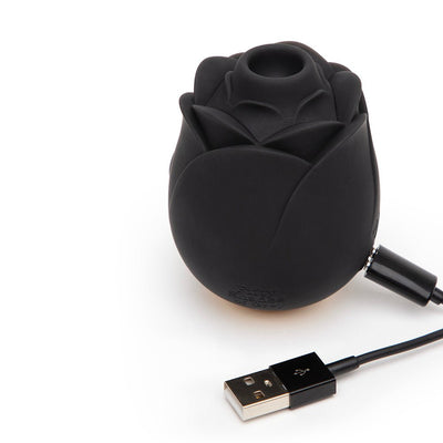 Black rose-shaped vibrator with USB charging cable on white background