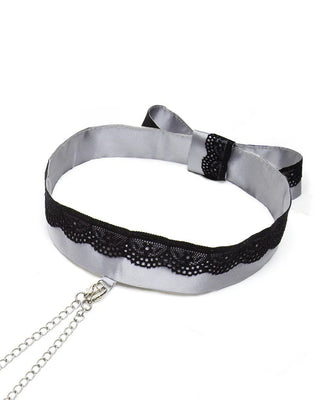 Grey satin collar with black lace trim and attached silver adjustable nipple clamps with chains on white background.