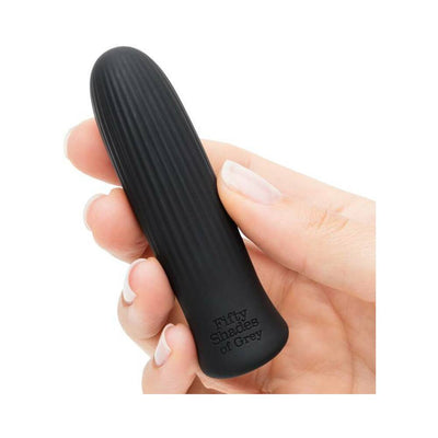 Hand holding a sleek black Fifty Shades of Grey bullet vibrator with a ribbed texture and rounded tip.