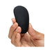 Hand holding a sleek black pebble-shaped Fifty Shades of Grey clitoral vibrator with textured surface.